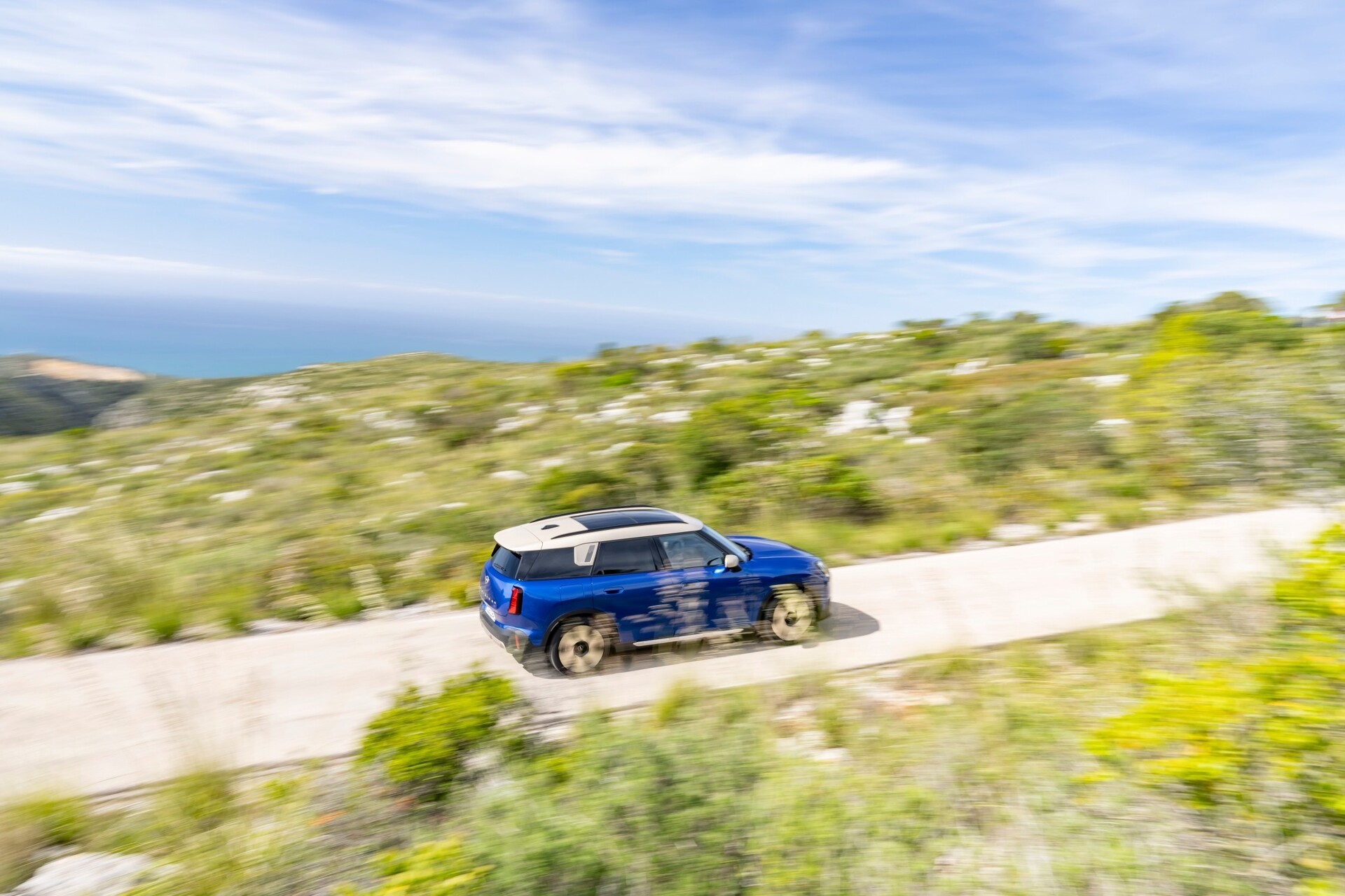 MINI Countryman E a circular na estrada no meio de paisagem natural.